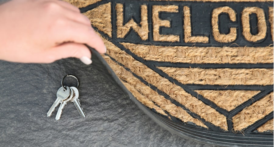 Placing house keys under a welcome mat